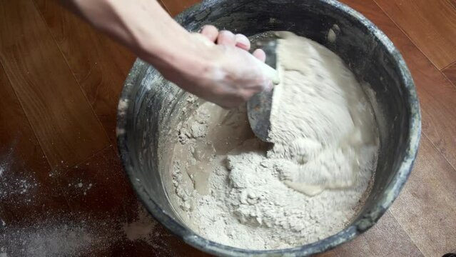 mixing of dry plaster mixture in a bucket with a trowel