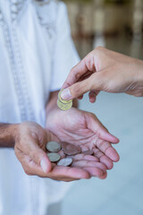 close up of hand giving some money to someone at the mosque