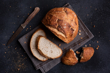 Loaf of bread freshly baked and cut on dark background