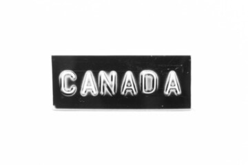 Black color banner that have embossed letter with word canada on white paper background