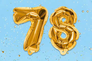 The number of the balloon made of golden foil, the number seventy-eight on a blue background with...