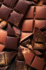 Chocolate pieces. Composition of bars and pieces of different milk and dark chocolate, grated and bean cocoa on black background. Baking Chocolate Texture.Top view with copy space. Mock up.