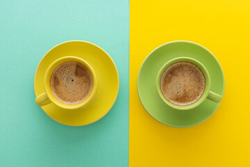Two cups of coffee on blue and yellow background. Top view. Minimalism coffee concept.