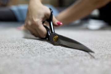 Close-up of a dressmaker cutting a piece of fabric with professional scissors in sewing workshop....
