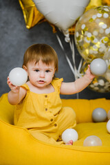 Obraz premium 1 year birthday baby playing with ball pool balls