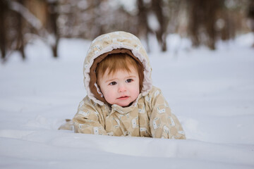 one year old baby girl sitting in deep snow in forest