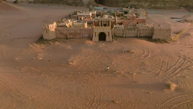 Aerial View Of Woman Running In The Desert Towards French fortress With Wadi Rum Sandstone In The Background In Jordan. - tilt up