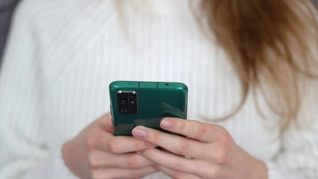 Close-up of beautiful female hands with phone. Typing message on modern smartphone