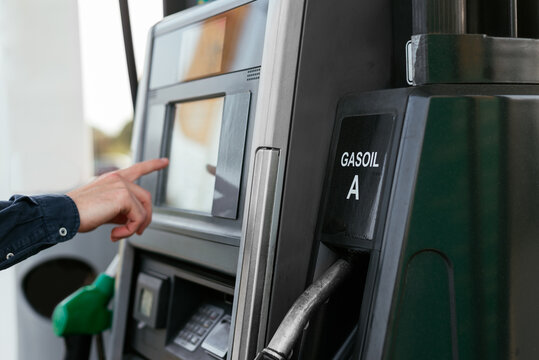 Anonymous person paying with card at machine in modern petrol station