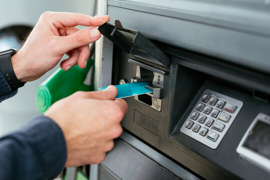 Anonymous person paying with card at machine in modern petrol station