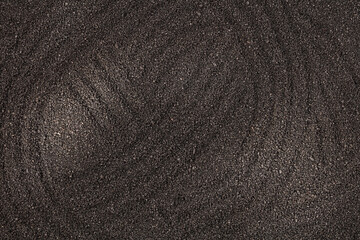 Black sand with traces and stripes may used as background. Top view