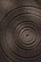 Fototapeta na wymiar Background of black sand with circles. Top view
