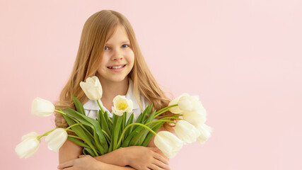 The concept of spring, happiness and holiday. Close-up portrait of a lovely smiling girl holding a bouquet of white tulips in her hands on a pink background