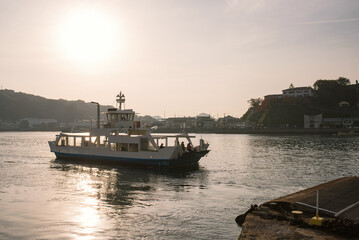 Obraz premium 広島県・尾道水道の夕景 尾道市街と向島を結ぶ渡し船 Ferryboat crossing Onomichi Waterway at sunset