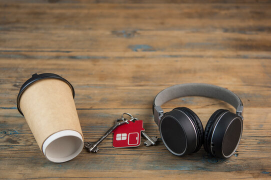 headphones with a paper cup of coffee on wood table.