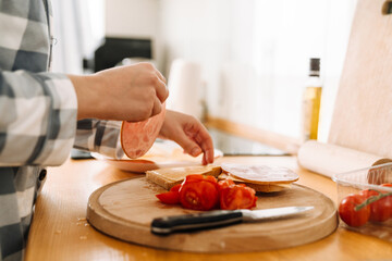 Young woman wearing pajama making sandwiches in kitchen