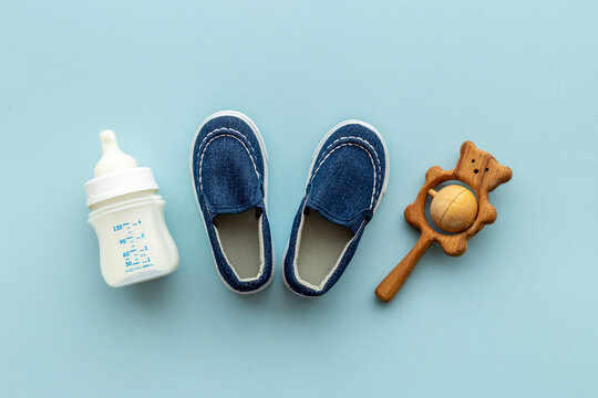 Baby newborn blue booties with bootle of milk and wooden toy