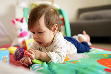 Close up on baby small caucasian girl five months old lying belly down on tummy at home in summer...