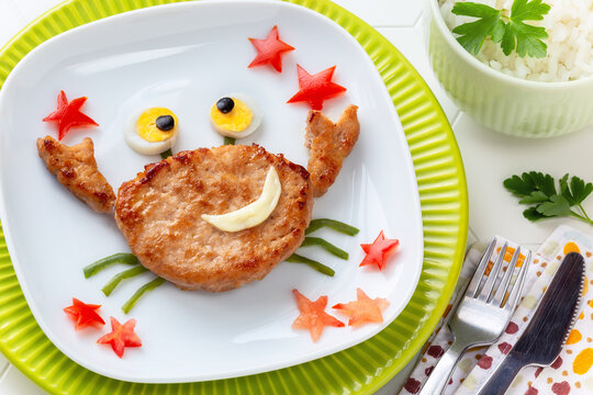 Fun Food for Kids - cute smiling crab shaped veal burger juggling with red starfish served with rice for a healthy lunch or dinner