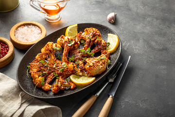 Vegetarian cauliflower steaks with microgreens and lemon on the plate. Alternative to traditional meat steaks for vegans.