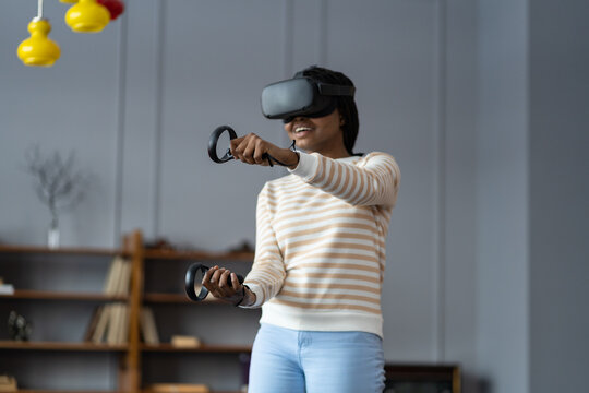 Excite black woman testing virtual reality device in digital world. College student girl hold controllers play shooter vr video game futuristic immersive simulator virtual reality 3D 360 cyber game