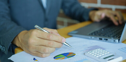 close up businessman  hand using  pen to pointing on spreadsheets report to show company profit...