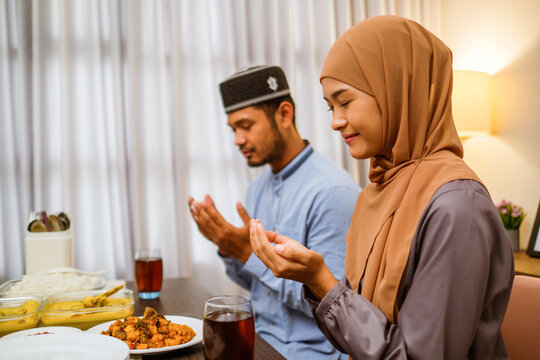 muslim couple people praying before break fasting iftar dinner together at home in ramadan celebration