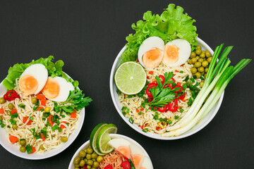 Beautiful Noodle Dish with Green Onions, Eggs, Green Pea, Red Hot Pepper, Greens and Lime on Sushi Mat. Instant Noodles with Vegetables