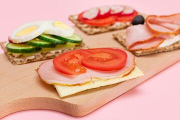 Different Whole Grain Crispbread with Ham, Tomato, Radish, Cucumber and Cheese. Easy Breakfast. Diet Food. Quick and Healthy Sandwiches. Crispbread with Tasty Filling. Healthy Dietary Snack