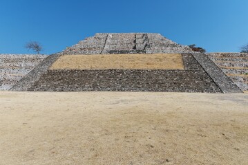 Fototapeta na wymiar Ancient step pyramids on top of a mountain. Cleared meadows with grass. Pyramid stonework, architecture. City in Mexico Xochicalco