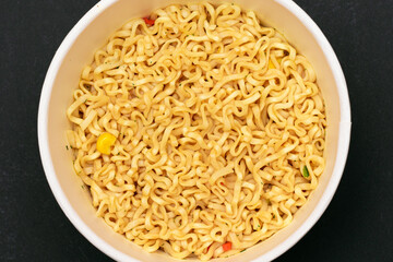 Instant Noodles in Disposable Cup on Black Background - Top View. Asian Fast Food. Quick Lunch