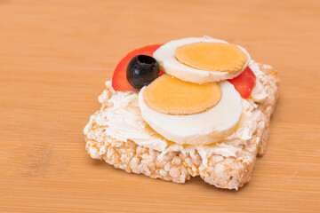 Rice Cake Sandwich with Tomato, Eggs and Olives on Bamboo Cutting Board. Easy Breakfast. Diet Food. Quick and Healthy Sandwiches. Crispbread with Tasty Filling. Healthy Dietary Snack