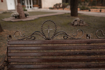 Bench in the park at the temple. Image of an Orthodox cross.