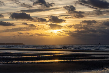 Fantastic view of the dark overcast sky. Dramatic and picturesque golden evening sunset scene over the sea. Storm clouds, storm passing over sea, dramatic clouds after storm at sunset. Defocused. High