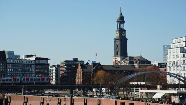 Hamburg Skyline with historic St. Michael's Church, aka Michel, and metro train crossing on a sunny day against a blue sky.