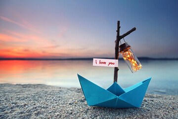 romantic evening - magical blue paper boat with lantern at the beach