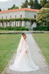 Portrait of the bride in a cream dress on the background of a luxurious mansion.