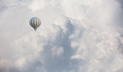 Classic type hot air balloon flying over the clouds