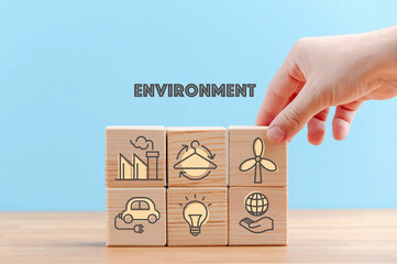 Circular economy concept, recycle, environment, reuse, manufacturing, waste, consumer, resource. Sustainable development. Hand put wooden cubes; the symbols of circular economy on blue background.