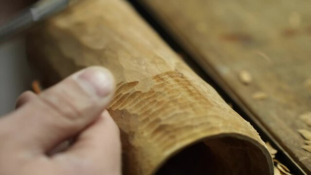 carver cuts wooden detail on woodworking chisel