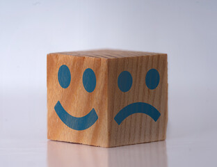 Photo of a wooden cube with happy and sad face expressions as a symbol of instat personality shifts. Concept of bipolar , unipolar and borderline mental disorder. - obrazy, fototapety, plakaty