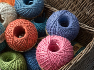 Focus on a pink ball of gardener's twine amongst other coloured balls in a wicker basket