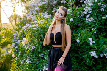 Lady in a summer dress on a near the bushes.
