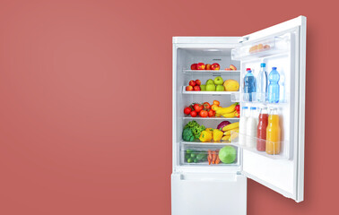 Open fridge full of vegetables, fruits and drinks on pink wall background. Copy space