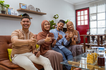 visiting friend and family during eid mubarak islamic day. beautiful of muslim family sitting in livingroom smile to camera and showing thumb up