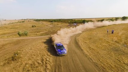 Low Flying Aerial Of Subaru Rally Car Drifting Around A Corner With Dust Flying