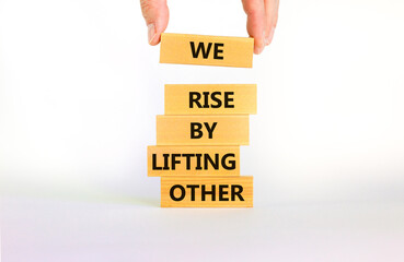 We rise by lifting other symbol. Concept words We rise by lifting other on wooden blocks. Businessman hand. Beautiful white background. Business we rise by lifting other concept. Copy space.