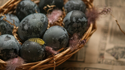 Easter card with a copy of the place for the text. Purple, blue eggs in a basket on a dark newspaper background. Natural dye karkade tea.