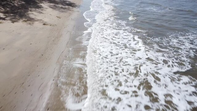 Drone flying low over waves on beach