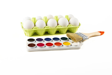 Egg cassette on a white background and a molar brush with watercolors. Humor about preparing to paint eggs for Easter.